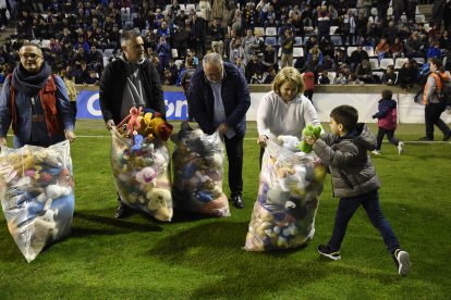 Un nen dona un peluix als voluntaris durant l’acte solidari en el descans.