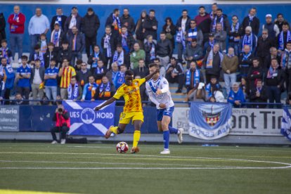 Quadri desplaça una pilota, amb la nombrosa afició lleidatana desplaçada al partit en el fons.