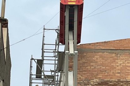 Un operari amb vestit de protecció per retirar el fibrociment de la coberta de l’Escola del Treball. A la dreta, part de la uralita que hi havia. Ara ja no en queda.