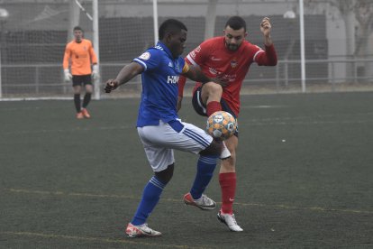 Un jugador del Lleida B lluita per la pilota davant d’un del Balaguer.