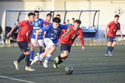 Un jugador de l’AEM condueix la pilota davant la pressió de dos jugadors rivals.