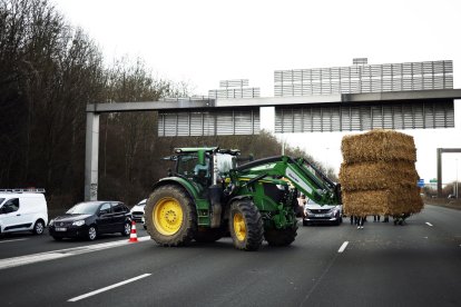 Un tractor descarrega farratge al mig de la carretera durant el bloqueig de l’autopista A15 a Argenteuil.