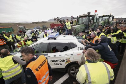 Un grup d’agricultors empeny un cotxe de la Guàrdia Civil que els impedia entrar amb els tractors en una carretera de Navarra.