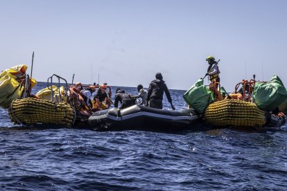 Els equips de rescat evacuen migrants a bord de l’embarcació inflable a la deriva.