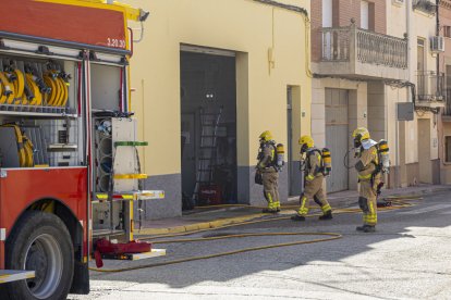 Tres efectius entrant a l’interior del garatge amb els equips de respiració autònoma.