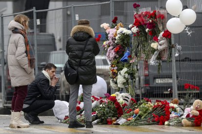 Una família russa deixa flors en un memorial als morts en l’atemptat a la capital de Rússia.