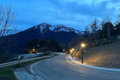 La vorera il·luminada de nit i els contenidors d’escombraries al fons.