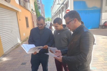 Tres dels inquilins repassen els documents del jutjat després de la vista oral celebrada ahir.