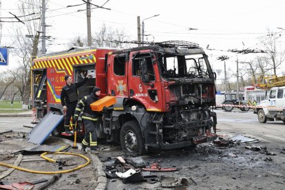 Dos bombers ucraïnesos, al costat d’un camió calcinat per un míssil a Khàrkiv.