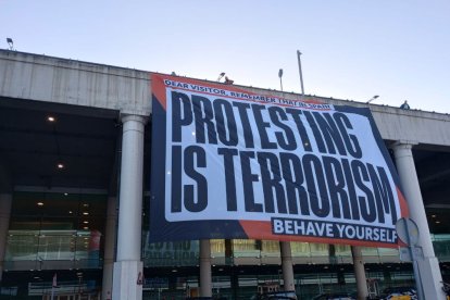 Òmnium va penjar una lona a l’aeroport del Prat amb el lema “a Espanya protestar és terrorisme”.