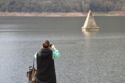 Una mujer fotografía el campanario de la iglesia del pantano de Sau, totalmente sumergida. - ACN