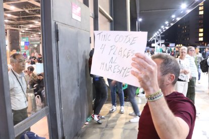 Un hombre con un cartel en que ofrece cuatro plazas al coche para ir al Maresme, delante de Sants de Barcelona