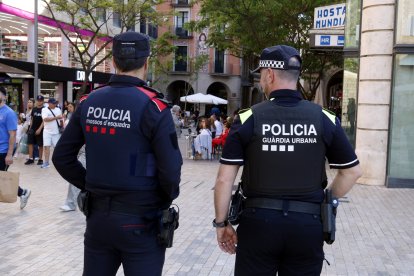 Un agente de los Mossos d'Esquadra y uno de la Guàrdia Urbana de Lleida en el Eix Comercial de Lleida.