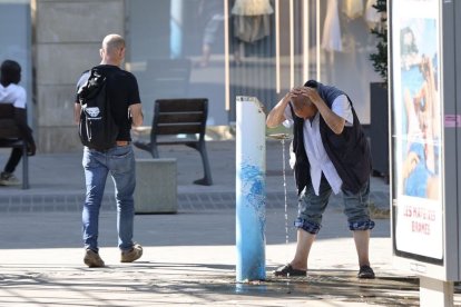 Una persona refrescant-se ahir en una font de Lleida. - AMADO FORROLLA