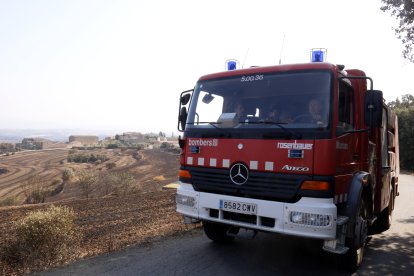 Un camió de Bombers a les proximitats del nucli de Guardiola, al municipi de Vilanova de l'Aguda, amb camps afectats per l'incendi de Torrefeta al fons.