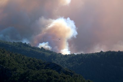 Un helicóptero tira agua en el Valle de Viñas de Paüls hacia donde se ha desplazado el incendio más activo.