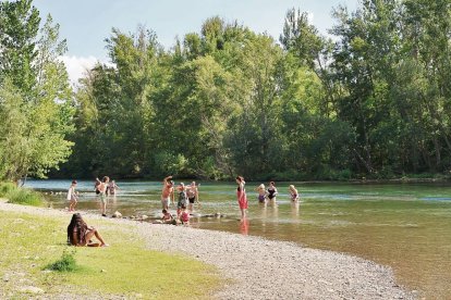 Un grup de banyistes passa la tarda de dijous al curs del riu Segre vora el pont romà de Camarasa.; Array