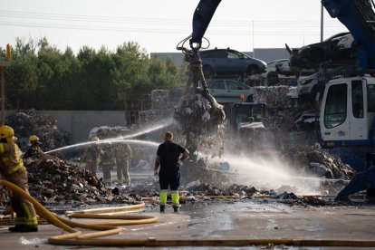 Efectivos de los Bomberos y operarios trabajando ayer en las tareas de extinción en la empresa en el polígono Camí dels Frares. - PAU PASCUAL PRAT