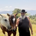 Pere Cases, amb dos dels cavalls retirats que cuida al seu refugi de Montcortès. - MARTA LLUVICH/ACN