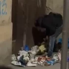 Un home escampant escombraries d’una bossa per la vorera.
