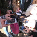 Joves muestran sus teléfonos móviles.