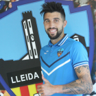 El nuevo jugador del Lleida Esportiu, Marc Trilles, posa ya con la equipación del club y junto al escudo.