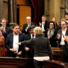 La diputada y exconsellera Irene Rigau, de espaldas, saluda al Govern mientras recibe una ovación en pleno del Parlament.