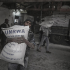 Un refugiado palestino lleva un saco con harina en un campamento de refugiados de Gaza.