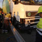 Operarios trabajando ayer por la tarde en el camión accidentado en la A-2 a su paso por Lleida.