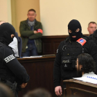 Agentes de policía enmascarados custodian en el tribunal a Salah Abdeslam, cuya cara está pixelada.