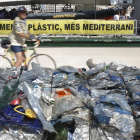 Un vaixell de l'organització Greenpeace al port de València davant d'un munt de bosses de plàstic.