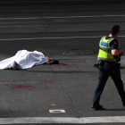 El cadáver de la víctima, en el suelo, custodiado por un policía.