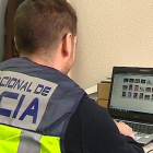 Un agent de la Policia Nacional revisa un ordinador requisat en l’operació.