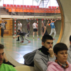 Alumnos de Inefc durante una clase teórica y tras ellos otros practicando voleibol en el pabellón.