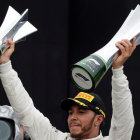 Lewis Hamilton, celebrando el triunfo en el podio con los trofeos.