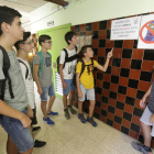 Alumnes de l’institut Joan Oró contemplen un cartell que prohibeix utilitzar el mòbil a tot el centre.
