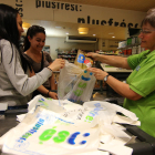 Una empleada d’un supermercat de l’Eix Comercial col·loca productes en una bossa de plàstic.