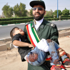 Un soldado iraní traslada a un niño herido después del atentado.