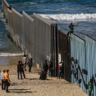 Imagen de la frontera sur de Estados Unidos con inmigrantes en el muro que parte ambos países.
