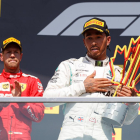Hamilton, en el podio con el trofeo de ganador, y Vettel, detrás, resignado tras la sanción. 