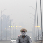 Un motorista circula per Nova Delhi protegit amb una màscara.