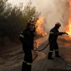 Varios bomberos tratan de extinguir un incendio en Penteli, al norte de la capital de Grecia.