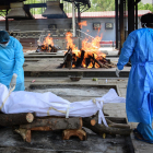 Dos operarios se disponen a quemar a el cuerpo de una víctimas del coronavirus en un crematorio en Nueva Delhi, India.