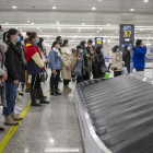 Pasajeros (con mascarilla) esperan para recoger su equipaje en el aeropuerto de Shanghái. 