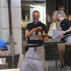 Un camarero con mascarilla y pantalla de seguridad en la cara, en una terraza en Figueres.