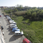 Imagen de la calle Marimunt, sin aceras y con varios coches aparcados junto a un solar con basuras. 