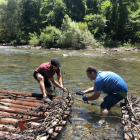 Dos vecinos construyendo el ‘rai’ que hoy descenderá por el río Noguera Pallaresa. 