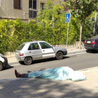 Imatge d'un home dormint a ple sol al barri.