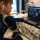 Un nen segueix una classe des de casa amb l’ordinador.