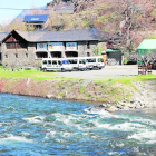 El río Noguera Pallaresa y al fondo, una empresa de deportes de aventura con las furgonetas paradas.